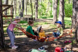 Four children enjoying and playing on a hammock in their backyard, representing the benefits of Mosquito, Flea, & Tick control.