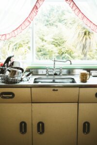 A kitchen counter with a sink and clean dishes on the side representing cleanliness as one strategy of pest control.