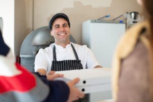 A smiling employee presenting a box to customers.