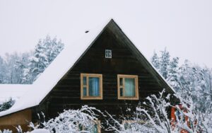 A rustic house with fresh snow on the roof.