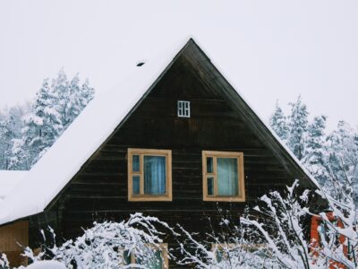 A rustic house with fresh snow on the roof.