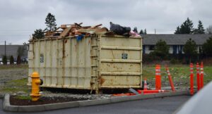 Large dumpster full of furniture, trash, and clutter that was serving as harborage for cockroaches and bed bugs, representing clean out phase of pest control plan.