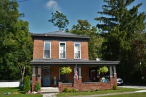 Historic brick 2 story farmhouse with tin roof and front porch, representing a pest free home.